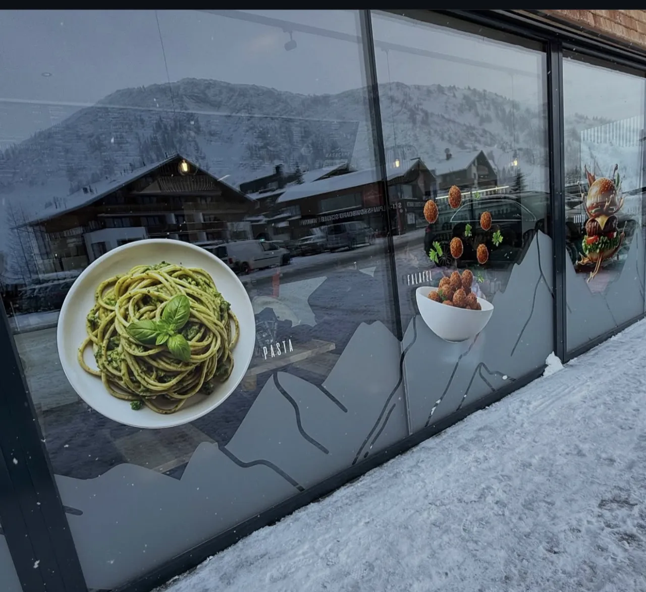 Weitere Schaufensterfront mit Pasta- und Falafel-Motiven und gezeichneter Bergkontur
