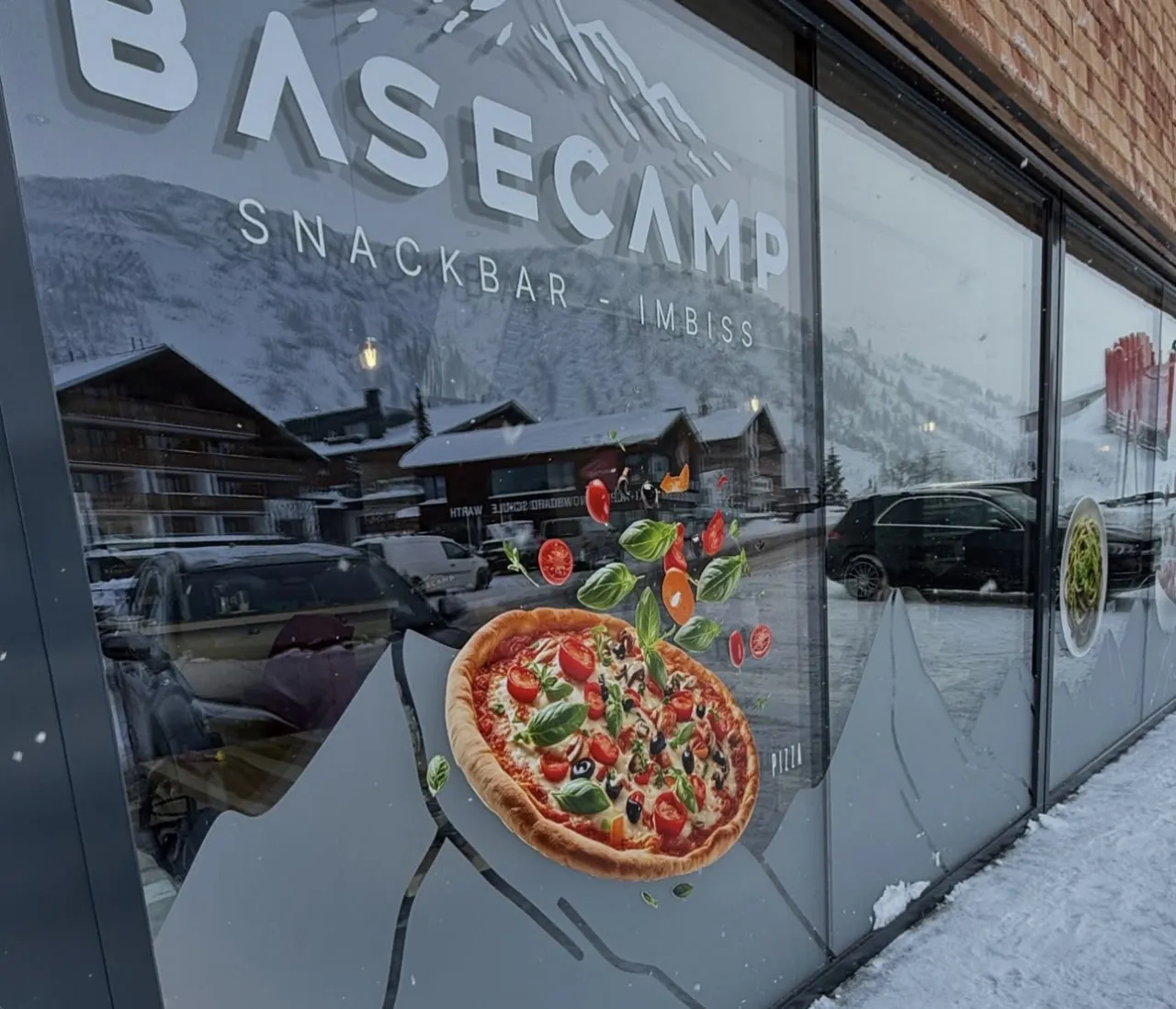 Schaufenster mit Pizza-Motiv und Schriftzug Basecamp Snackbar Imbiss