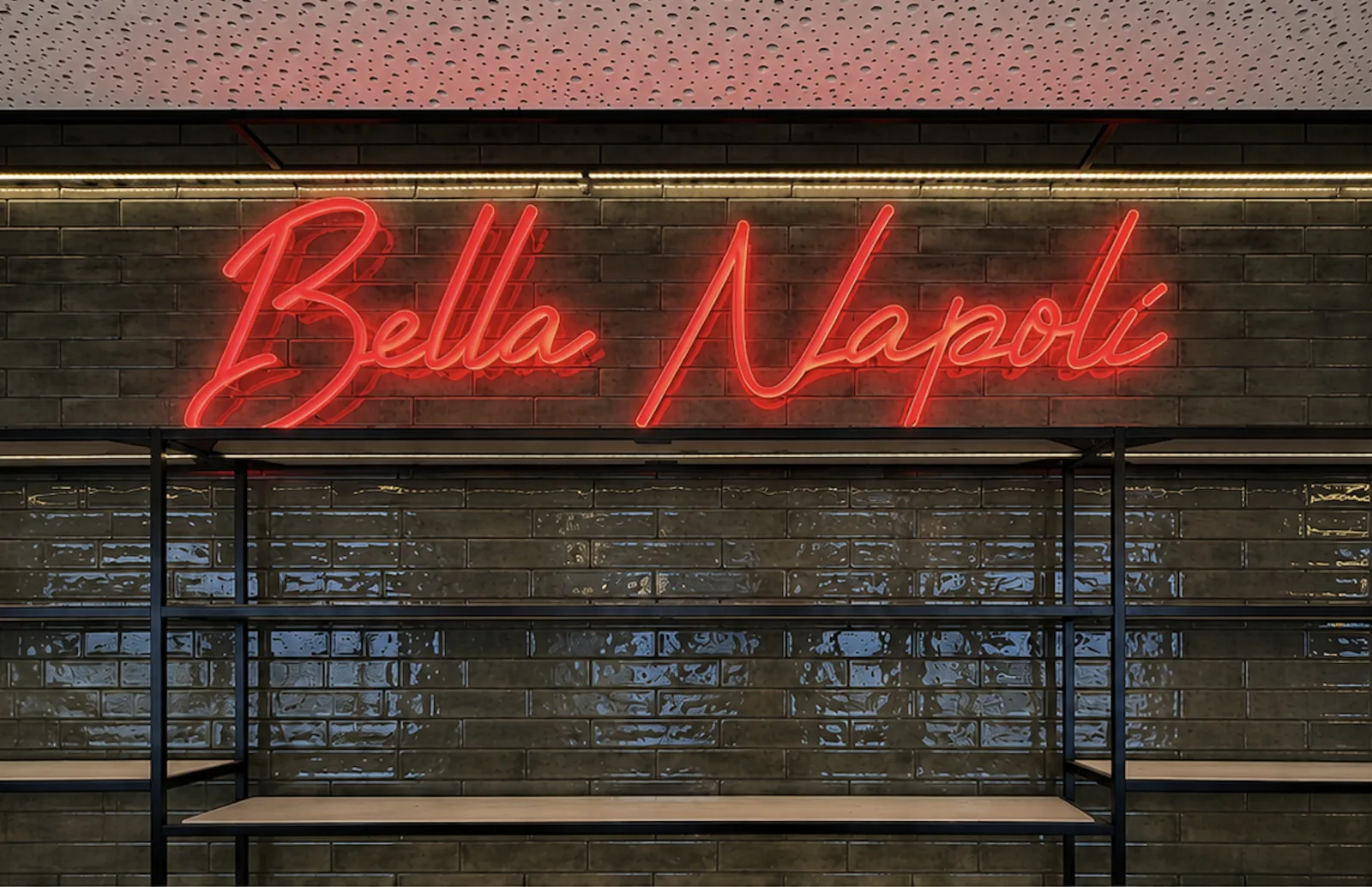 Derselbe Schriftzug Bella Napoli in Dornbirn eingeschaltet, rot leuchtend auf der dunklen Fliesenwand